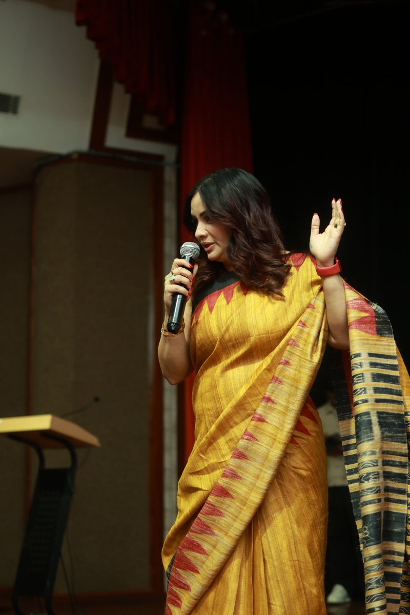 Roopali Talwar speaking on stage with a microphone during a mindset training session